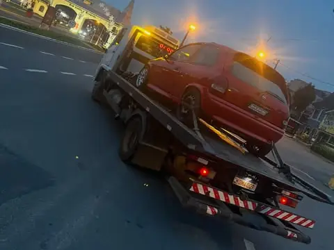 Guincho com carro vermelho na plataforma em avenida de Viamão ao anoitecer
